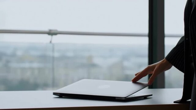 Business woman's hand gently touches the laptop cover, ready to shut down and leave