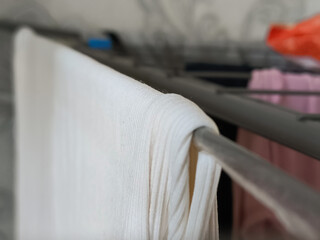Clean winter clothes hanging on dryer near light wall