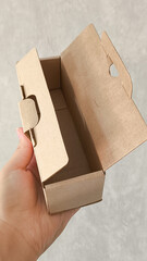 female hands holding a small cardboard box on a white background. packaging and delivery concept, top view