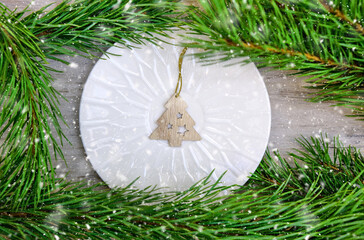 Christmas table setting with plate and Christmas wooden decorations. Snowing. Merry Christmas and Happy New Year