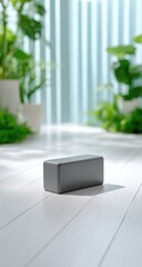 Gray block podium on white wooden floor, surrounded by plants and light teal curtains