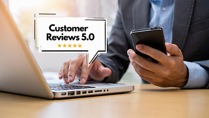 Man using laptop with customer reviews pop up and holding a mobile phone in the other hand