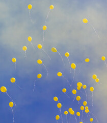 Fototapeta premium A group of yellow balloons flying in the air against a blue sky background