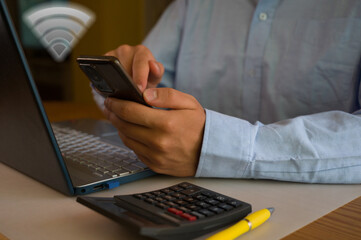 Businessman using smartphone and laptop in office. Man scrolls social media, checks email, manages...