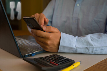 Businessman using smartphone and laptop in office. Man scrolls social media, checks email, manages...