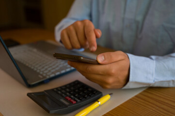 Businessman using smartphone and laptop in office. Man scrolls social media, checks email, manages...
