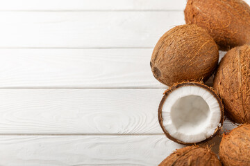 Set of fresh whole and half coconuts and slices on wooden background. Coconut flakes. Vegan. Tropical nut, fruit. Place for text. Copy space.