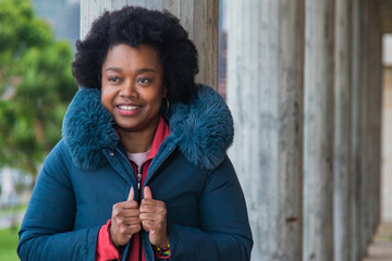 Portrait of a black woman smiling outside, in the park. wearing autumnal clothes