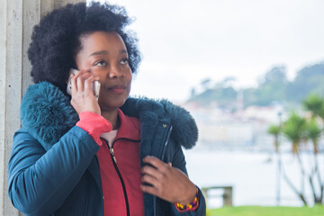 Young woman wearing a winter jacket talking on her mobile phone in the park