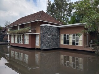 A building built over a pond. The reflection of buildings on the water creates a striking visual...