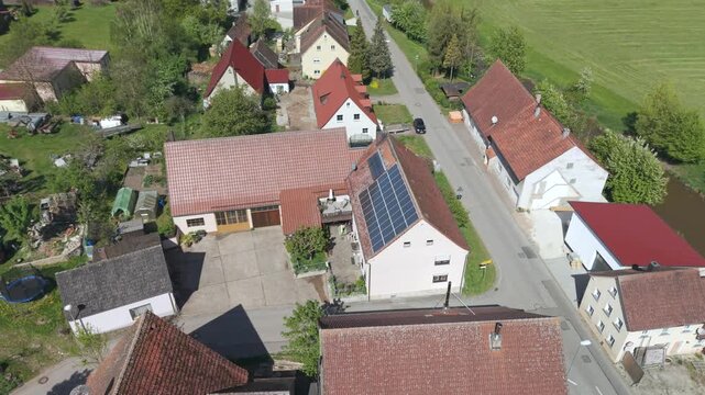 A drone fly over during Spring across a small Franconia village called Thann nearby Ansbach embedded in green landscape and and a small river