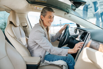 Smiling woman behind the wheel of her eco friendly electric car