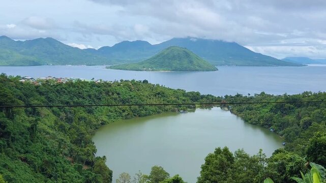 Ngade Lake, Ternate, North Mollucas, Indonesia. Beautiful green lake with two mountains and ocean in the background