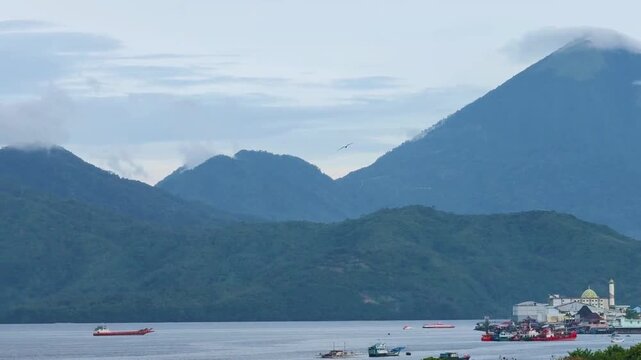 A boat sailing in middle sunny day with beautiful mountain in the background. Tidore Island, North Mollucas, Indonesia