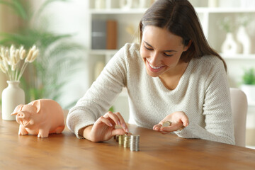 Happy woman counting coins from piggy bank at home