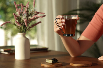 Woman hand holding tea cup at home at sunset