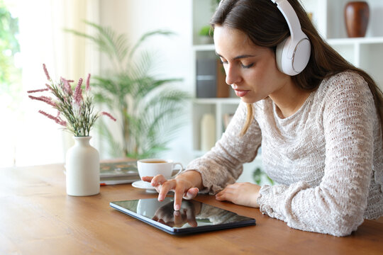 Woman with headphone checking tablet content at home