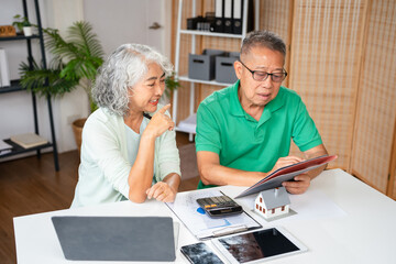 Senior old couple holding documents reading paper bills paying bank loan online, calculating...