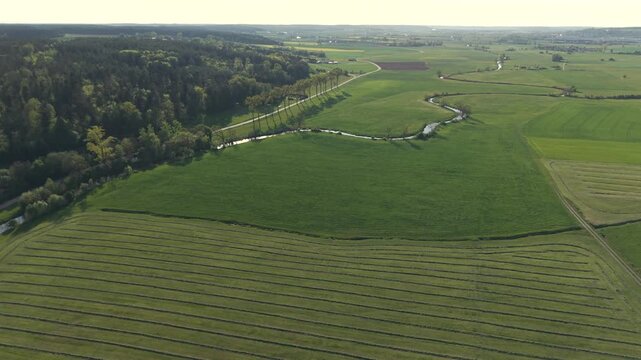A drone fly over during Spring across a small Franconia village called Thann nearby Ansbach embedded in green landscape and and a small river