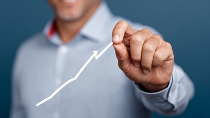 Man is drawing a line on a blue background, which appears to be a graph. The line is pointing upwards, which could represent growth or progress. The man's hand is in the air