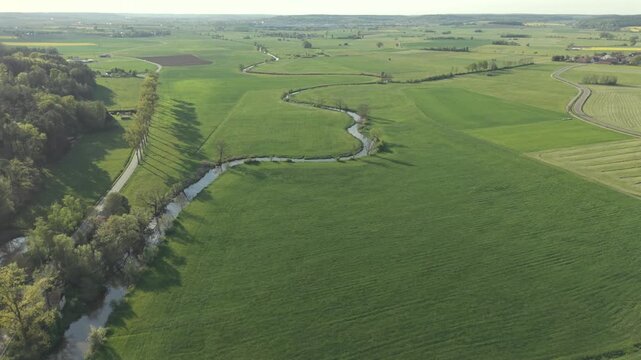 A drone fly over during Spring across a small Franconia village called Thann nearby Ansbach embedded in green landscape and and a small river