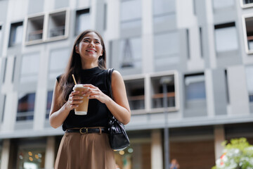 Smiling businesswoman holding coffee walking in business district
