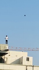 boy flying kite from the roof top