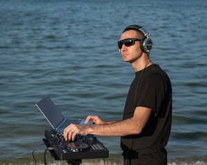 Male DJ playing music on the beach. 