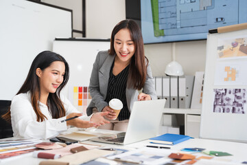 Two creative office employees choosing material and  making interior design on laptop computer in...