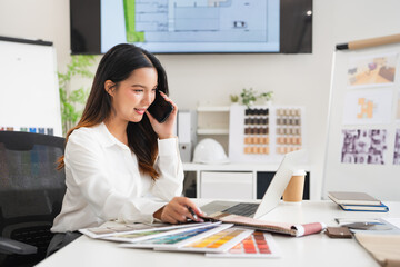 Designer working in office and making call on mobile phone. Female interior designer talking by...