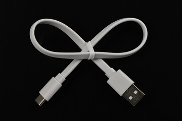 White USB cable in bow shape on black acrylic background.