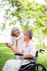Hand in hand. Senior woman standing next to the wheelchair and holding hand of her beloved disabled...