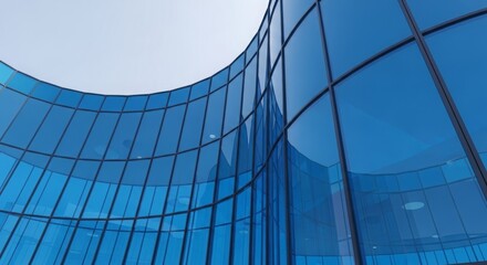Obraz premium Modern architectural design featuring curved blue glass facade reflecting the sky and surroundings