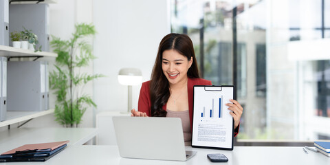  Young Asian businesswoman work at desk in modern office and virtual video conference meeting with...