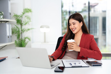 Smiling young asian businesswoman drink coffee enjoy morning in office. Happy female small business...
