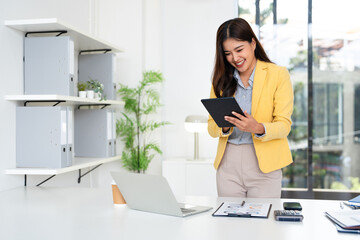 Successful businesswoman using digital tablet and laptop working at desk in office. Professional...