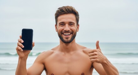 Smiling man at the beach holding a smartphone, enjoying a sunny day with ocean waves in the background