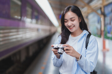 Young asian woman taking photos at train station with vintage camera