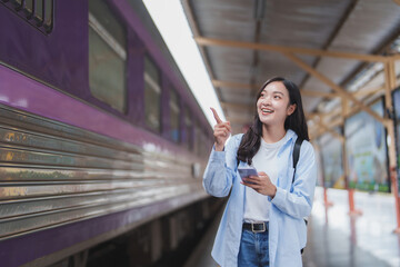 Young woman pointing finger near a purple train at station