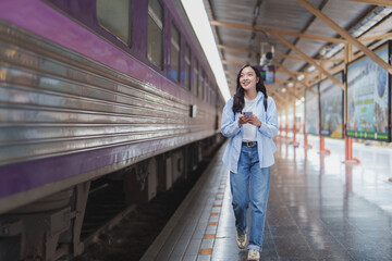 Young woman walking and using smartphone in train station