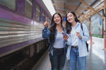 Young women traveling by train are checking platform number on smartphone
