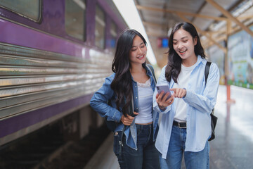Two young women consulting smartphone in train station