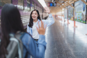 Young woman waving goodbye to friend at train station