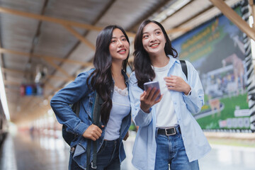 Two young tourists consulting mobile phone in train station