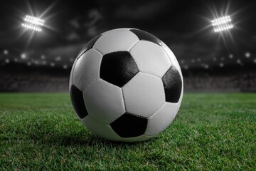 Soccer ball on green grass under stadium lights at night