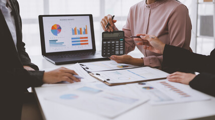 Businesswomen calculating tax using calculator and laptop in office meeting