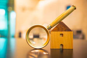 Magnifying glass and looking at house model, house selection, real estate concept.