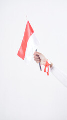 A woman hand with red and white Indonesia flag color attribute holding mini Indonesia flag decoration to celebrate Indonesia independence day celebration isolated on white background