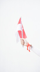 A woman hand with red and white Indonesia flag color attribute holding mini Indonesia flag decoration to celebrate Indonesia independence day celebration isolated on white background