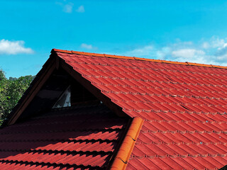 New construction home with a red tile roof, dormer window, and brick chimney against a blue sky